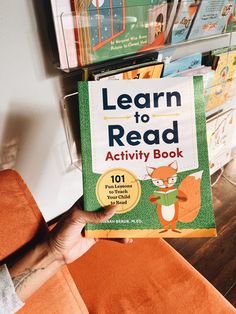 a person holding up a book in front of a stack of children's books