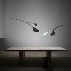 three suspended lights hang from the ceiling above a wooden table in an empty room with tile flooring