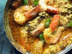 a pan filled with shrimp and vegetables on top of a stove