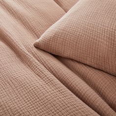 a close up view of a bed with brown sheets and pillows on top of it