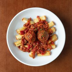 a white plate topped with meatballs covered in marinara sauce on top of french fries