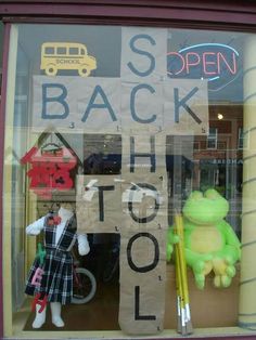 there is a window display with stuffed animals in the front and behind it are signs that say back to school