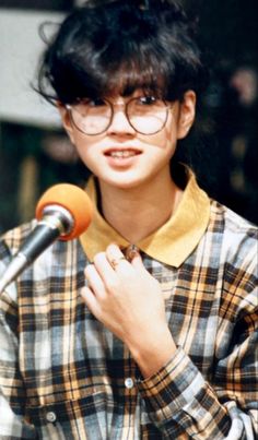 a woman wearing glasses and holding a microphone