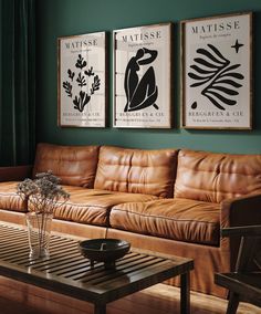 a living room with leather couches and paintings on the wall above them, along with a coffee table