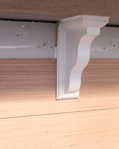 the corner of a wall with white molding on it's side and wood floor