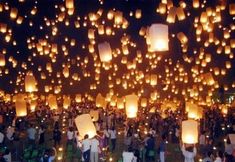 many people are flying lanterns in the night sky with lights on them and there is no image here to provide a caption for