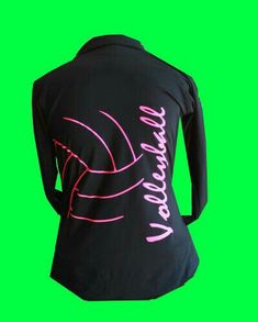 the back of a woman's black shirt with pink writing on it, against a green background