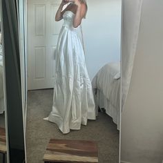 a woman in a white dress taking a selfie with her cell phone while standing in front of a mirror