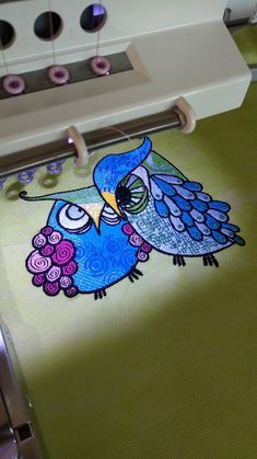 an image of a blue bird on a green table cloth being sewned onto a machine