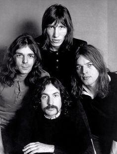 an old black and white photo of four men with long hair posing for the camera