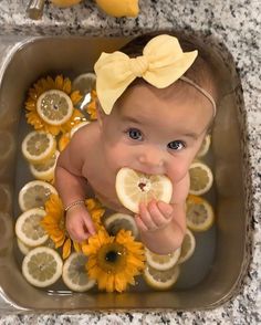 a baby in a bath with lemon slices and sunflowers