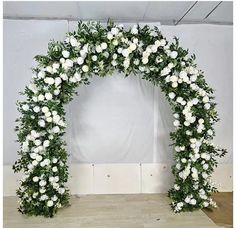 a white floral arch with greenery and flowers