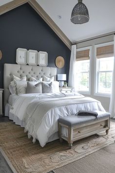 a large bed sitting in a bedroom on top of a carpeted floor next to two windows