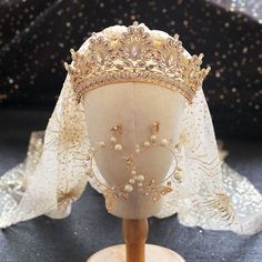 the headpiece is adorned with pearls and gold beads, along with an elaborate veil