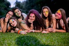 a group of young women laying on top of a lush green field next to each other