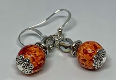 Gorgeous orange swirled beaded earrings accented by silver caps and mirrored silver faceted beads! These elegant earrings can go from day to night and dress up any outfit. They are hung on hypoallergenic nickel free ear wires. Perfect for fall, but able to be worn in any season! Elegant Nickel-free Orange Earrings, Nickel-free Orange Beaded Dangle Earrings, Halloween Orange Nickel-free Earrings, Nickel-free Orange Earrings For Halloween, Orange And Silver, Vintage Orange Nickel-free Earrings, Colored Earrings, Silver Caps, Pumpkin Colors