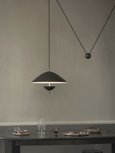 a dining room table with two lights hanging from it's sides and plates on the table