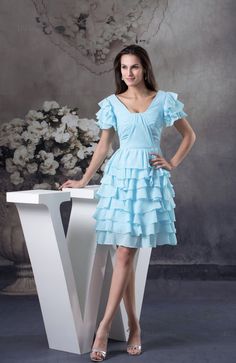 a woman in a short blue dress standing next to a table