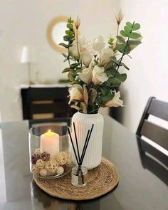 a white vase filled with flowers on top of a table next to a lit candle