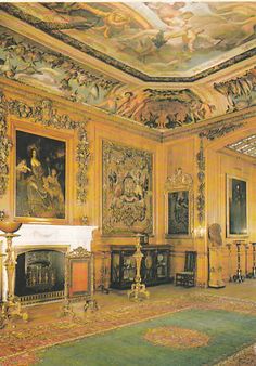 an ornately decorated living room with gold walls and ceilinging, along with paintings on either side of the fireplace