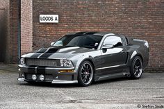 a black and silver sports car parked in front of a brick building