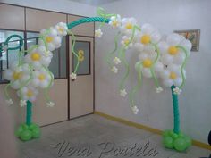 some white flowers and green balloons in front of a door