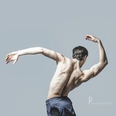 a man with no shirt is playing frisbee in the air on a gray background