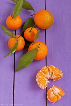 oranges and leaves on a purple wooden surface