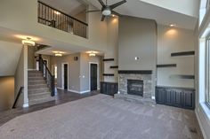 an empty living room with stairs leading up to the second floor and a large window