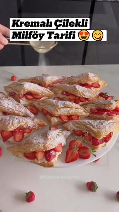 a person holding a spoon over a plate with strawberries and pastries on it