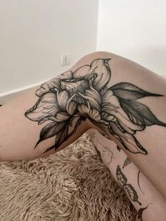 a woman laying on the floor with her legs crossed and flowers tattooed on her thigh