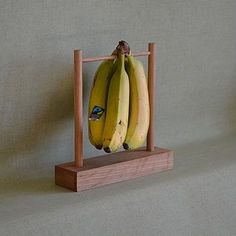 two bananas are hanging from a wooden frame on the wall next to another banana that has been placed in front of it