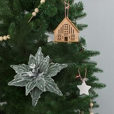 a christmas tree with ornaments hanging from it's branches and a house ornament on top