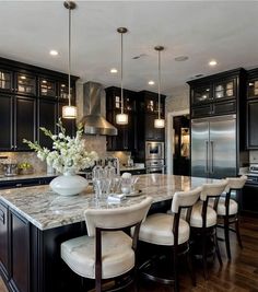 a large kitchen with black cabinets and marble counter tops