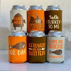 six can coolers with different designs and sayings on the cans are lined up in a row