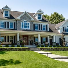 a large white house with lots of windows and shutters on the front, grass in front