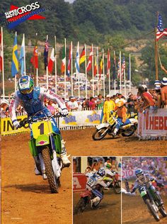 a group of people riding dirt bikes on top of a dirt field with flags in the background