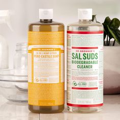 two bottles of liquid sitting on top of a counter next to a potted plant