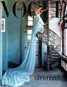 a woman in a white dress is standing at the top of a spiral stair case