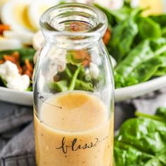 a glass jar filled with dressing next to a salad