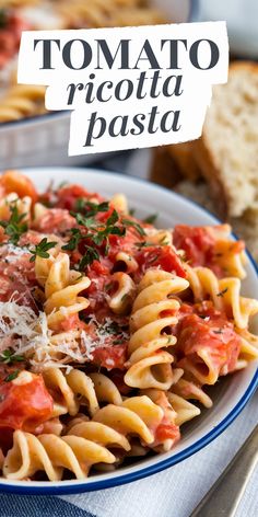 a plate of pasta with tomato sauce and parmesan cheese on top, next to bread