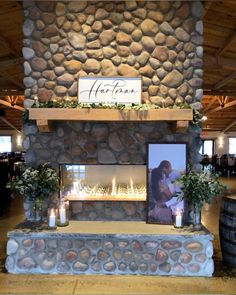 a man and woman are kissing in front of a stone fireplace with candles on it