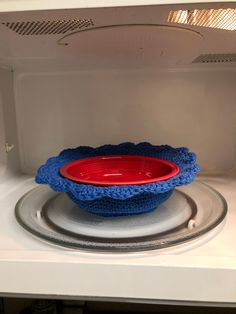 a red and blue bowl sitting on top of a white plate in a microwave oven