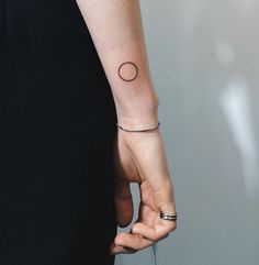 a woman's hand with a small circle tattoo on it