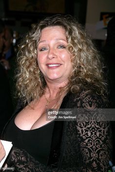 a woman with curly hair smiling and posing for the camera at an event stock photo