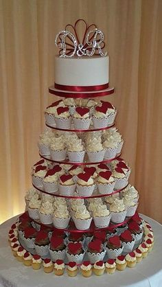 a tiered cake with cupcakes on top is decorated in red and white