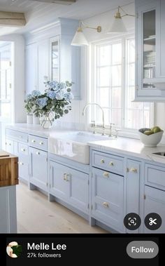 a white kitchen with blue cabinets and an island in the middle is featured on instagram