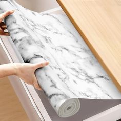 a roll of white marble paper being held by someone's hand over a drawer