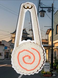 a white bag with an orange circle on it hanging from a pole in front of some houses