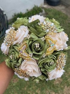 a bridal bouquet with brooches and flowers on the grass in front of a building